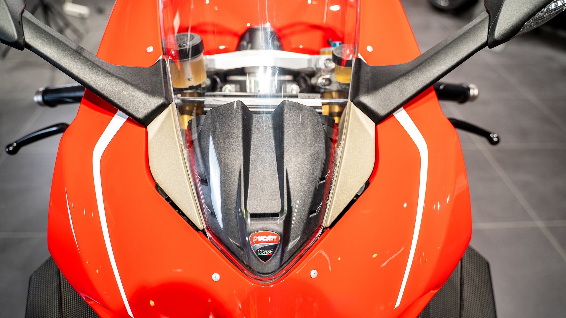 Zdjęcie przedstawia zbliżenie na przód motocykla w okolicach kierownicy. Ma trójkątne kształty, widoczna niska przednia szyba.  