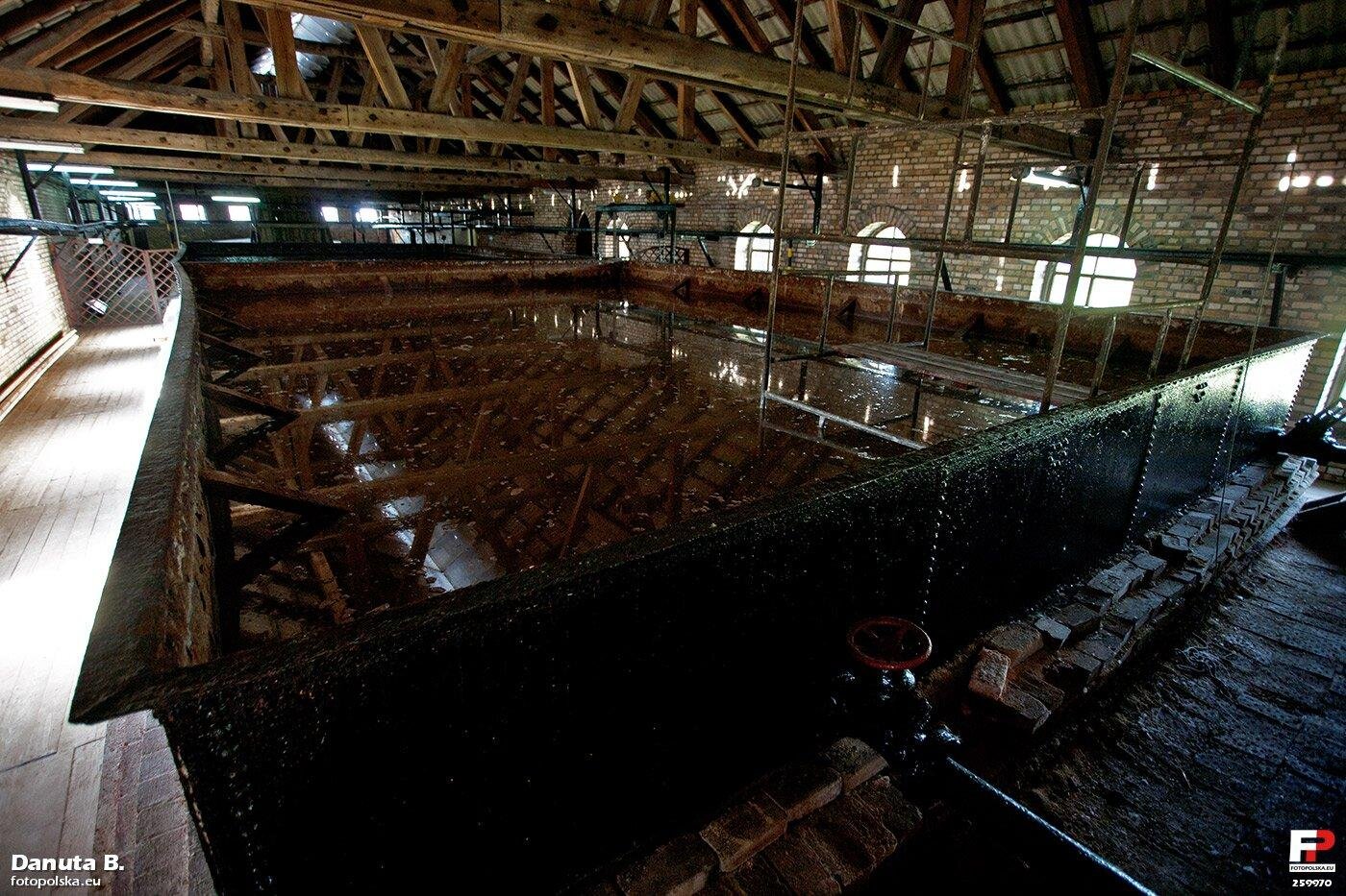 Zdjęcie przedstawia warzelnię soli w Ciechocinku. Ukazane jest obszerne pomieszczenie. Znajdują się w nim zbiorniki z wodą i drewnianymi konstrukcjami.