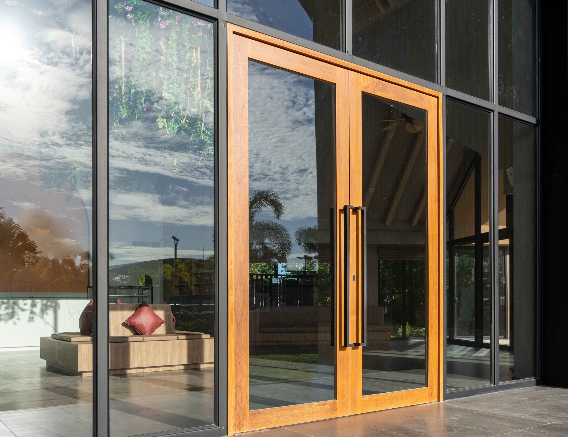 Zdjęcie przedstawia dwuskrzydłowe masywne drzwi o drewnianych ramach, które poza tymi elementami są całkowicie wykonane ze szkła.