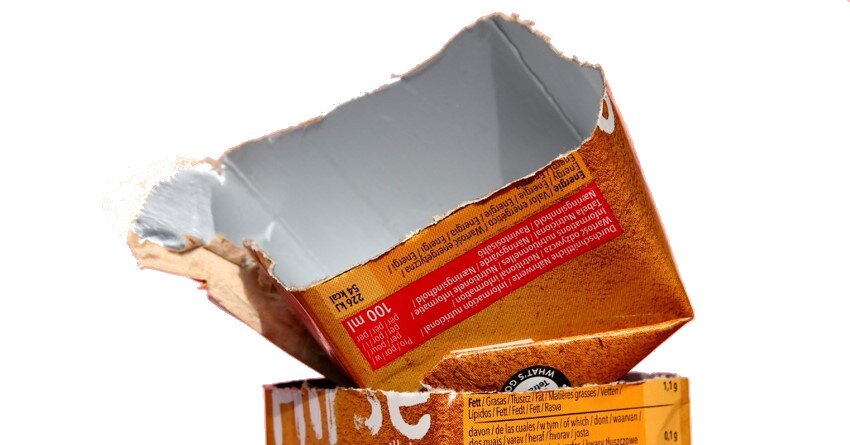 Zdjęcie przedstawia przerwane opakowanie do żywności płynnej zabezpieczone warstwą aluminium i polietylenu. Opakowanie wewnątrz jest srebrne, a na zewnątrz posiada nadrukowane informacje o produkcie. 