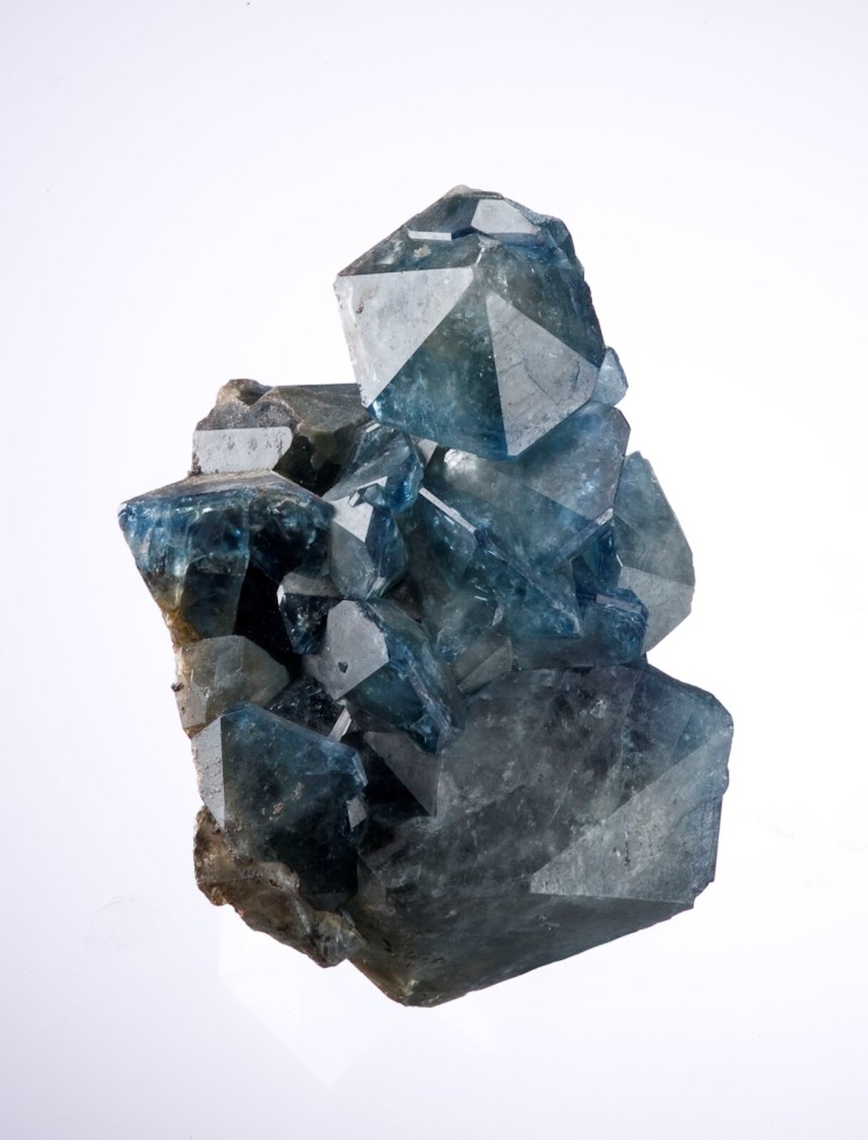 Zdjęcie przedstawia minerał fluoroapatyt. Ma niebieski kolor, jest przezroczysty i błyszczący. Kryształy są miejscami nieregularnie pozrastane, tworzą skupisko. 