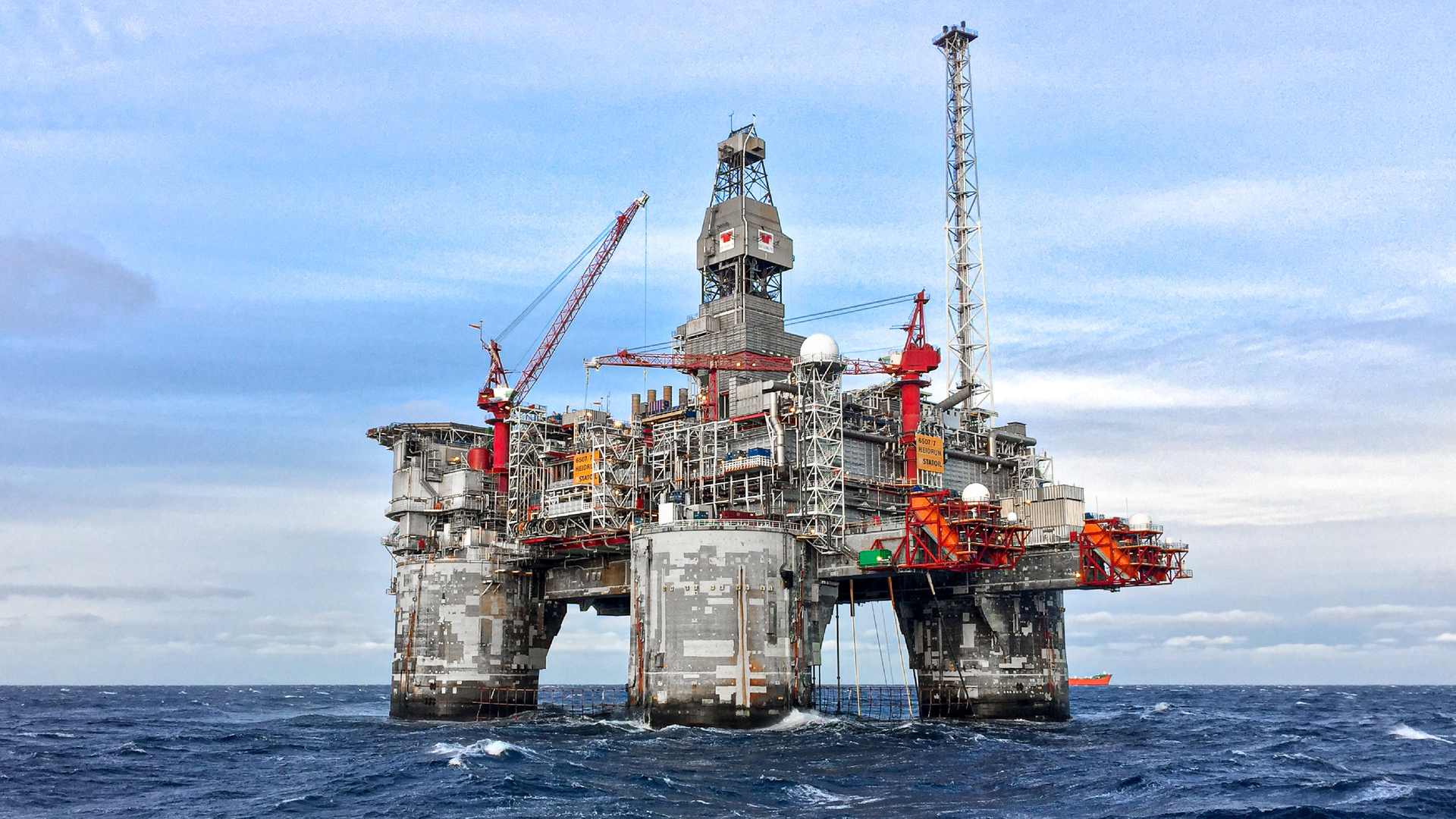 Zdjęcie przedstawia widok na platformę wiertniczą znajdująca się na morzu. Na platformie widoczna jest wieża oraz dźwig. 