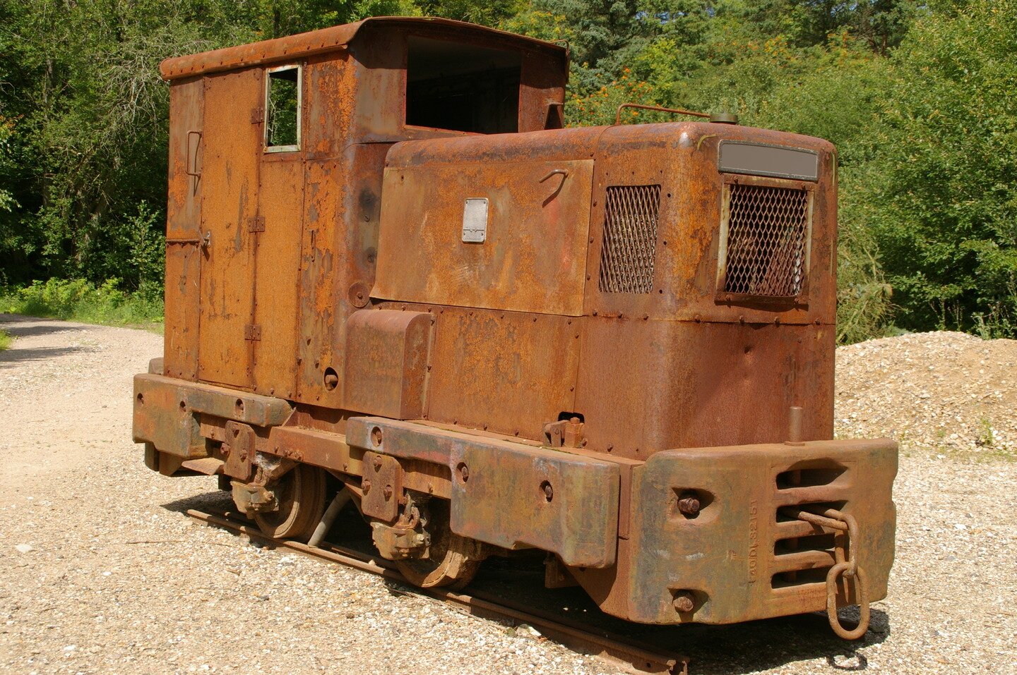 Ilustracja przedstawia zardzewiałą małą, starą lokomotywę.