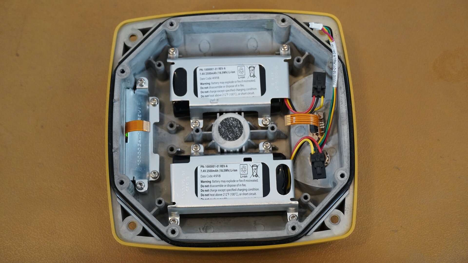 Na zdjęciu przedstawiono wnętrze odbiornika GNSS po odsłonięciu płyty głównej. W dolnej części obudowy widoczne są dwie baterie oraz złącza modułu. 