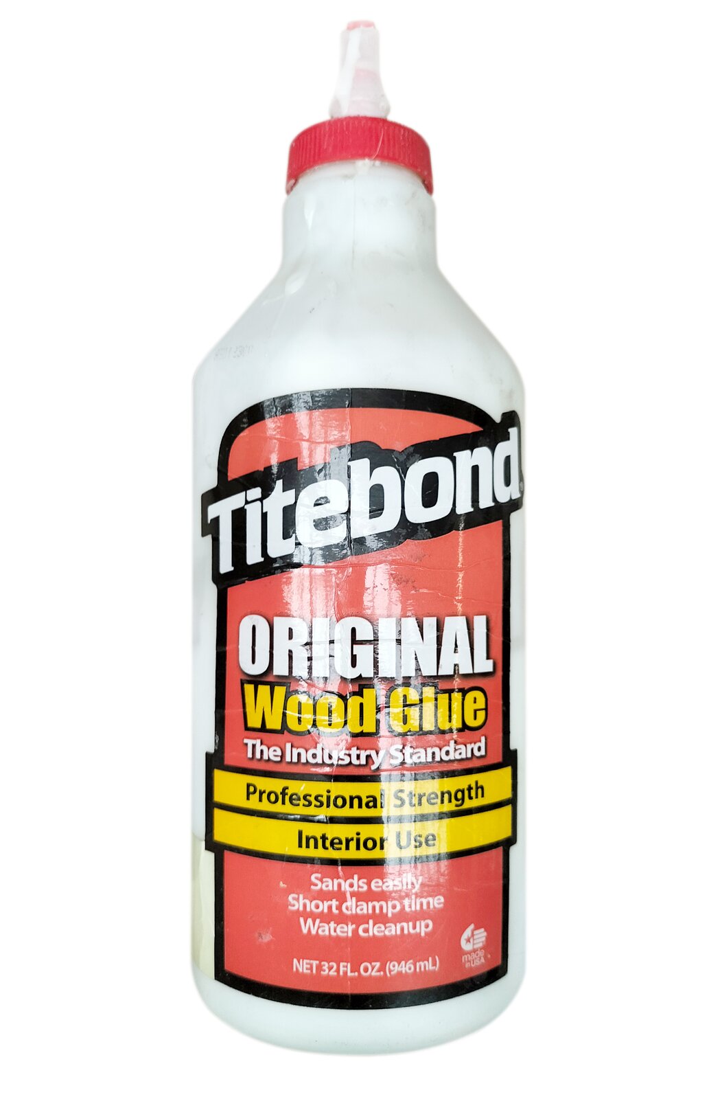 Zdjęcie przedstawia klej Titebond stosowany w stolarce oraz w trakcie korekty pianin i fortepianów. Widoczna jest biała butelka z czerwoną nakrętką oraz pionowym, białym elementem dozującym pośrodku nakrętki. Na butelce widoczna jest czerwona etykieta z białymi i żółtymi napisami, u góry mikro Titenbond.