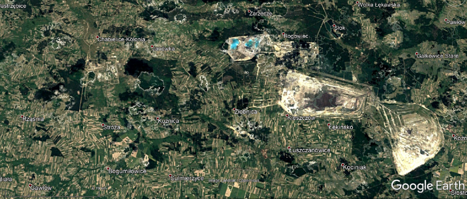 Na zdjęciu satelitarnym jest Zagłębie Górniczo‑Energetyczne Bełchatów–Szczerców–Złoczew w 1990 roku. Na zdjęciu jest jasnożółty prostokąt, po jego prawej stronie jest wzniesienie. Wyrobisko naziemne jest większe niż w roku 1984.  