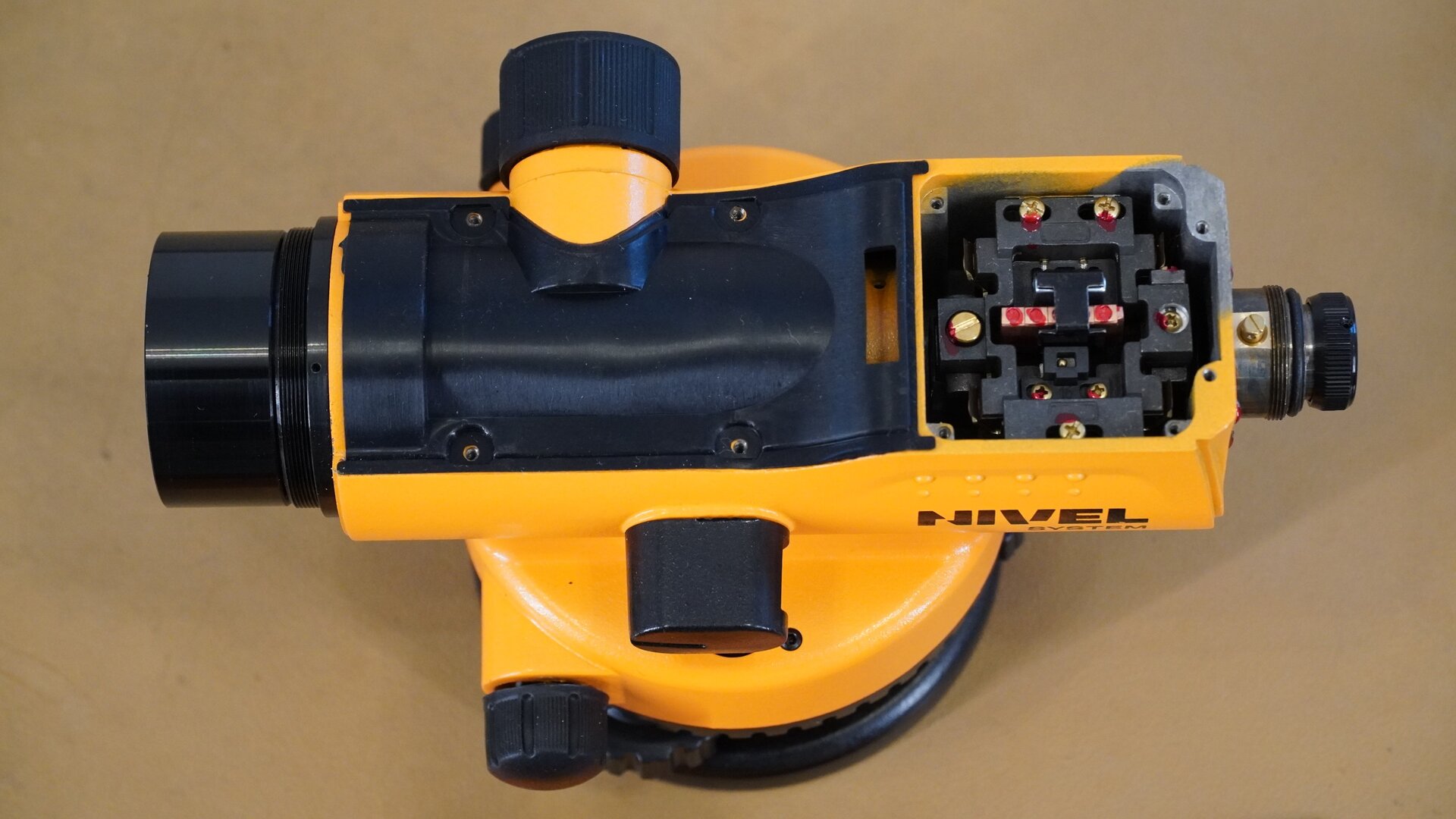 Na zdjęciu przedstawiono widok niwelatora z góry po demontażu osłony. Dzięki temu uwidoczniono kompensator umieszczony tuż za okularem.