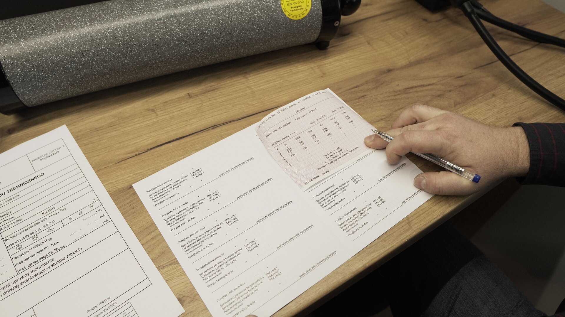 Na zdjęciu technik do wypełnionego paszportu technicznego dołącza wydrukowany wynik kalibracji spirometru.