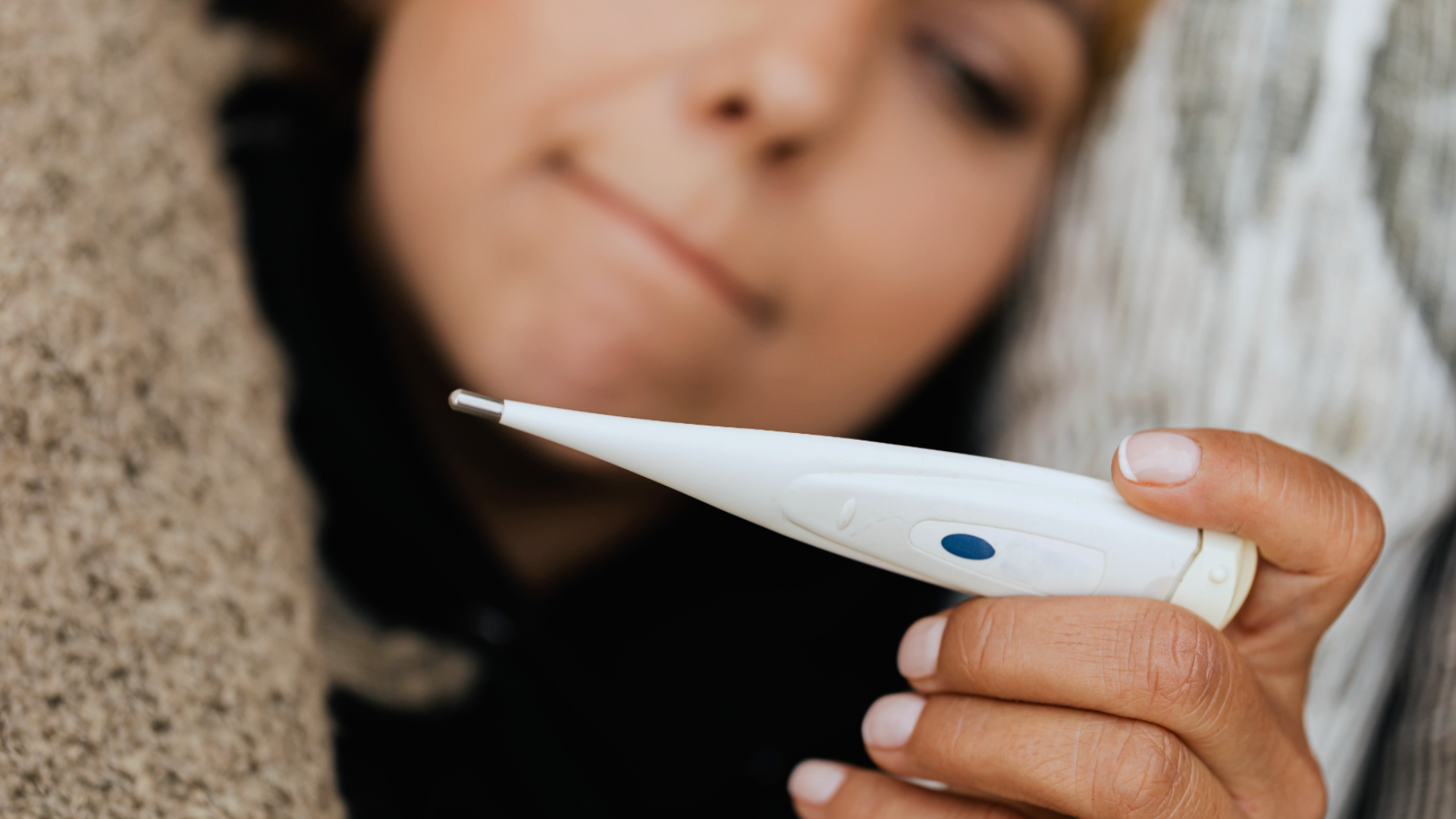 Zdjęcie przedstawia kobietę spoglądającą na termometr.