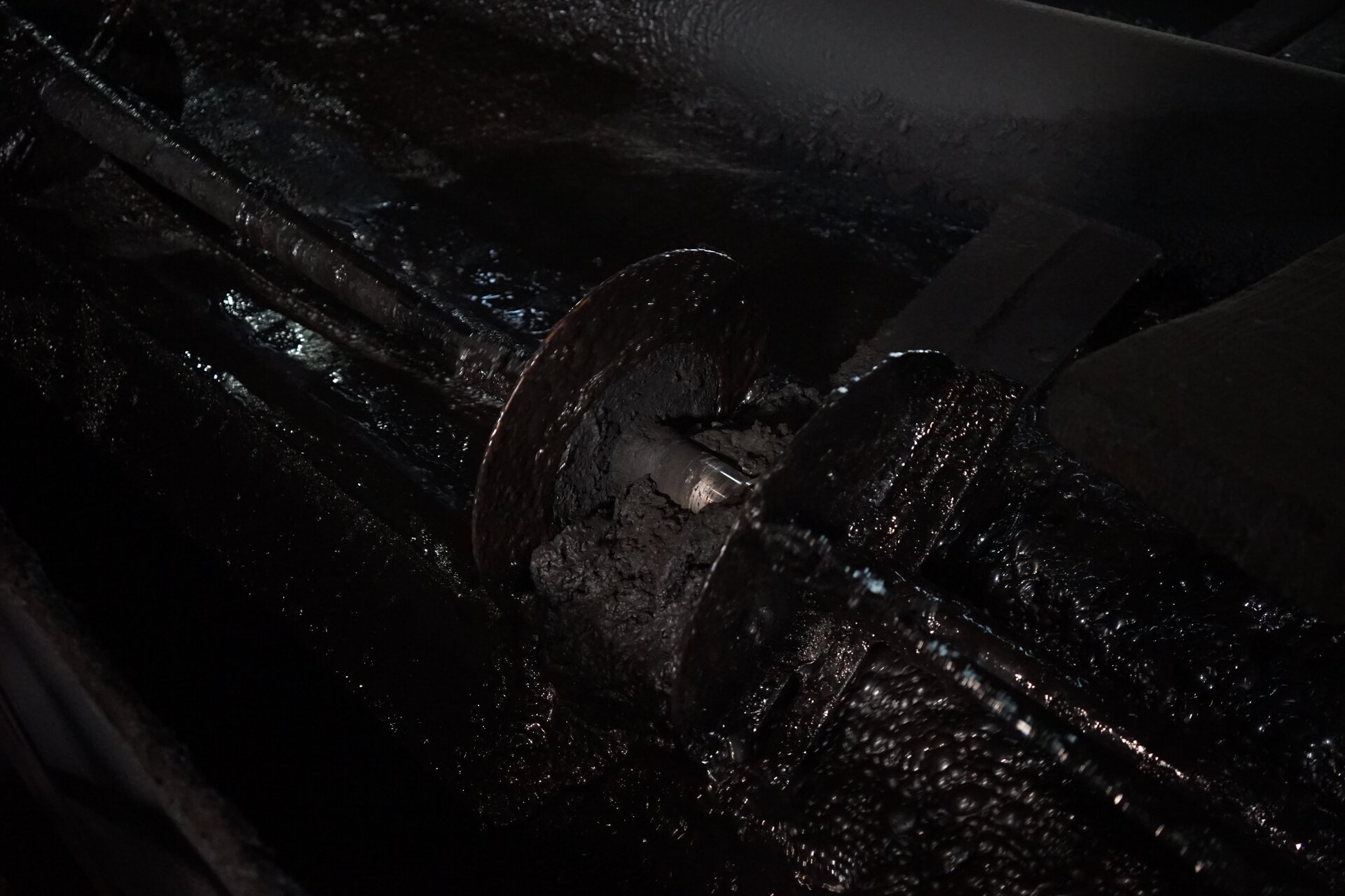 Zdjęcie przedstawia pianę flotacyjną utworzoną we wnętrzu flotownika podczas wzbogacania węgla surowego. Na środku znajduje się zgarniacz skrzydełkowy odpowiadający za wynoszenie piany bogatej w koncentrat poza maszynę flotacyjną. Łopatki zamocowane na zgarniaczu oblepione są pianą pokrytą czarnymi ziarnami węgla. Piana wydaje się gęsta oraz lepka wypełnia całą komorę.