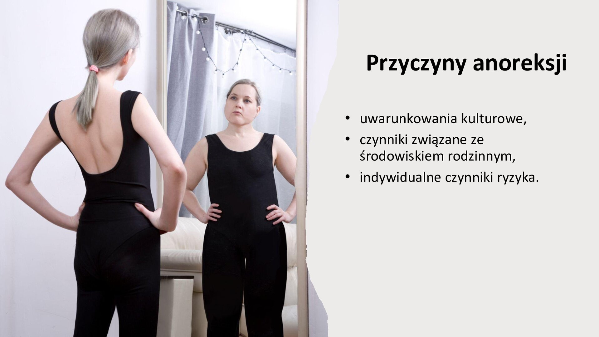 Jasnoszary slajd. Z lewej strony zdjęcie przedstawia młodą, szczupłą kobietę ubraną w czarny kombinezon. Wpatruje się w swoje odbicie w lustrze, które wygląda inaczej, gdyż ma nadwagę. Z prawej strony slajdu tekst: „Przyczyny anoreksji. Uwarunkowanie kulturowe. Czynniki związane ze środowiskiem rodzinnym. Indywidualne czynniki ryzyka”.