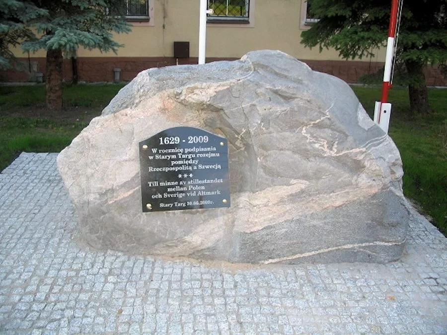 Kliknij, aby powiększyć. Na ilustracji przedstawiono duży jasnoszary głaz z przymocowaną doń czarną, kwadratową tablicą kamienną, z zaokrągloną górną krawędzią. Na tablicy dwujęzyczny napis - po polsku i po szwedzku. Tekst polski brzmi: "1629‑2009. W rocznicę podpisania w Starym Targu rozejmu między Rzeczpospolitą a Szwecją. Stary Targ 30. 05. 2009 r."