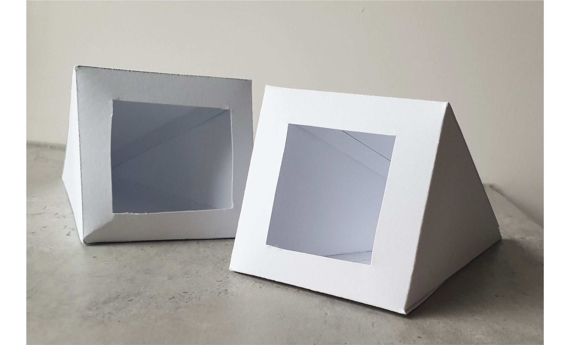 Zdjęcie przedstawia dwa modele ostrosłupów, o podstawie czworokąta wykonane z papieru. W podstawach ostrosłupów wycięto prostokątne otwory. Wnętrze ostrosłupów jest puste.