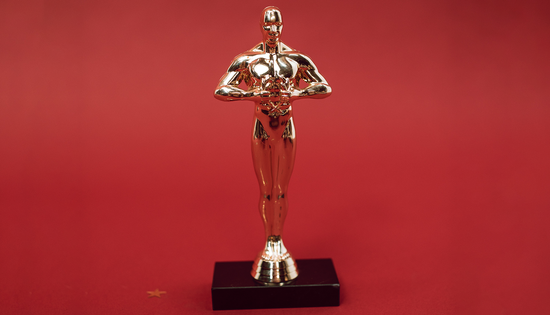 Zdjęcie przedstawia statuetkę Oskara ustawioną na tle czerwonego sukna.