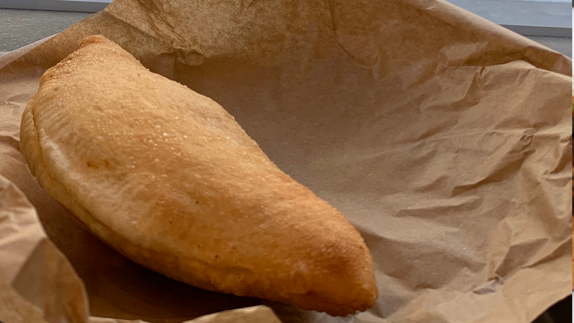 Zdjęcie przedstawia włoski pieczony pieróg. Pieróg leży na kawałku papieru.