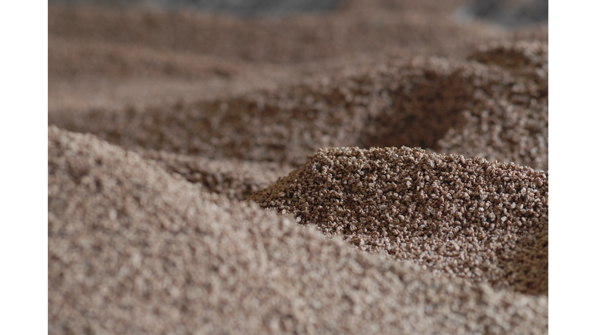 Drobno zmielony granulat. Zdjęcie. Zbliżenie na małe grudki biomasy, wyglądającej jak mokry piasek.