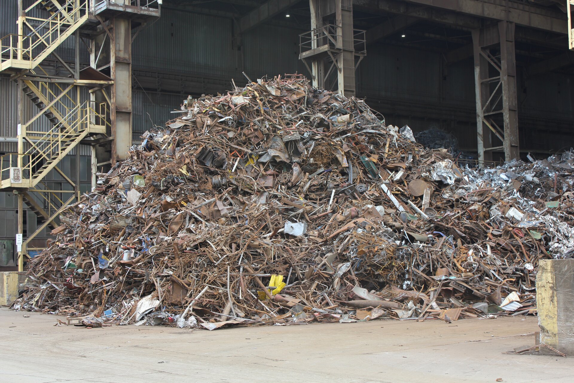 Obrazek jest fotografią sterty złomu, wysoka jest na około pięć metrów, składa się z metalowych, zardzewiałych i starych elementów.