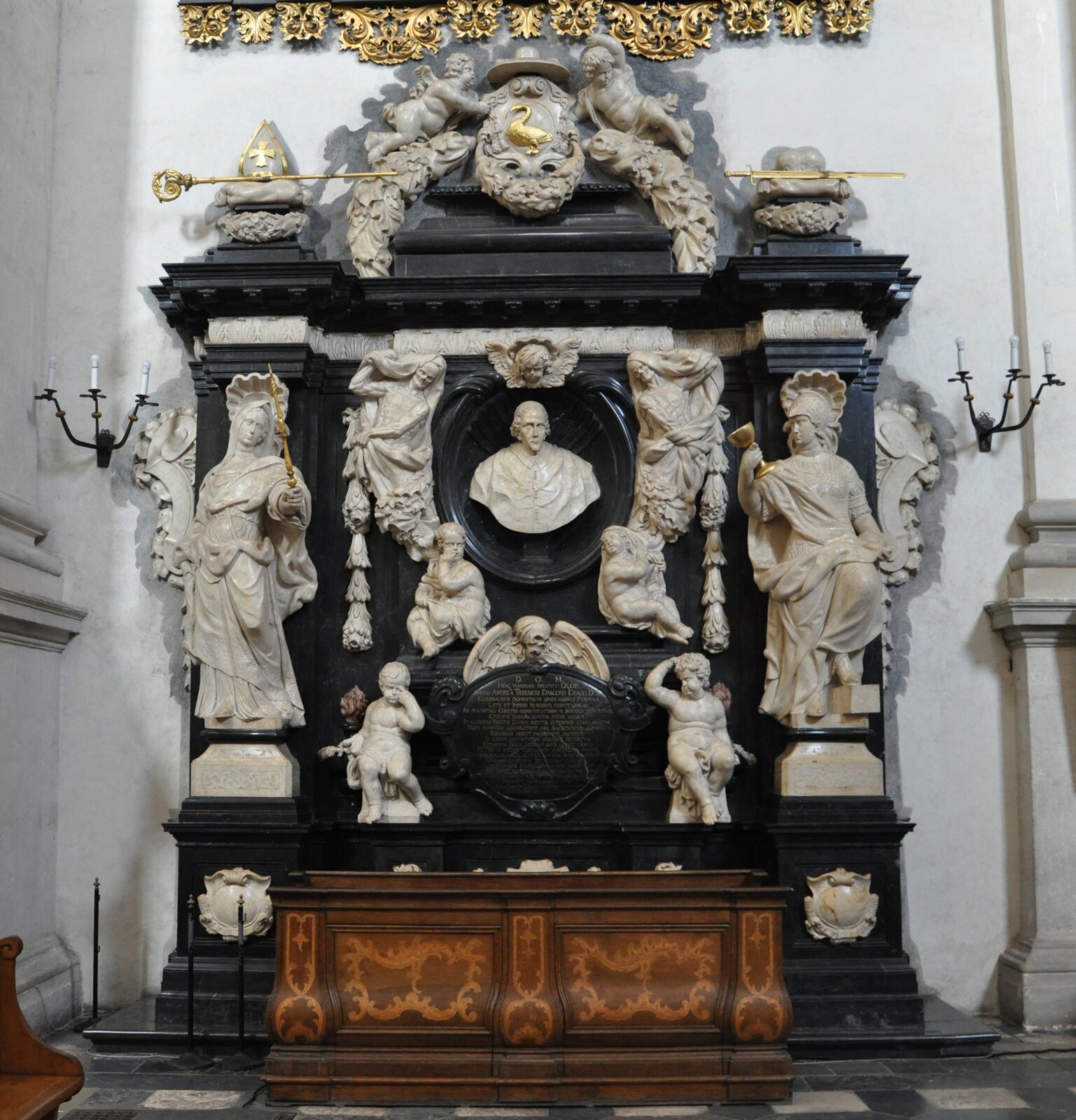 Ilustracja o kształcie kwadratu przedstawia nagrobek biskupa Andrzeja Trzebickiego. Ten jednokondygnacyjny nagrobek wykonany jest z trzech kolorów kamienia. Tło architektoniczne to czarny marmur. Składa się z części głównej, centralnej oraz nastawy. Po bokach na cokole zamieszczono pilastry z kobiecymi figurami. Zwieńczenie podtrzymywane jest przez dwa aniołki z girlandami, między którymi znajduje się herb ze złotym łabędziem. U dołu części centralnej znajduje się sarkofag, a nad nim tablica z tekstem, pośrodku zaś czaszka ze skrzydłami. Wyżej w owalnej ramie z głową anioła, przy której siedzą dwa inne aniołki, znajduje się popiersie biskupa.