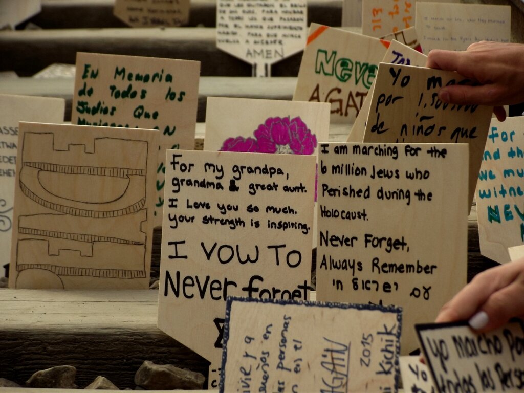 Fotografia barwna przedstawiająca drewniane tabliczki, na których uczestnicy Marszu Żywych upamiętnili ofiary Holocaustu.