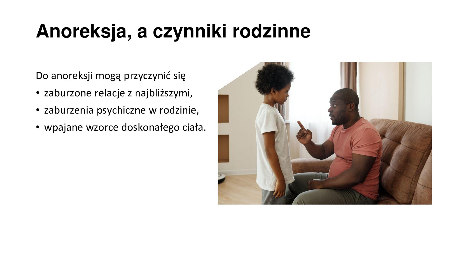 Biały slajd. Z prawej strony slajdu zdjęcie przedstawiające mężczyznę siedzącego na kanapie. Wpatruje się w stojącego przed nim chłopca i unosi do góry palec wskazujący prawej dłoni. Z lewej strony slajdu tekst: „Anoreksja a czynniki rodzinne. Do anoreksji mogą przyczynić się: zaburzone relacje z najbliższymi, zaburzenia psychiczne w rodzinie, wpajane wzorce doskonałego ciała”.