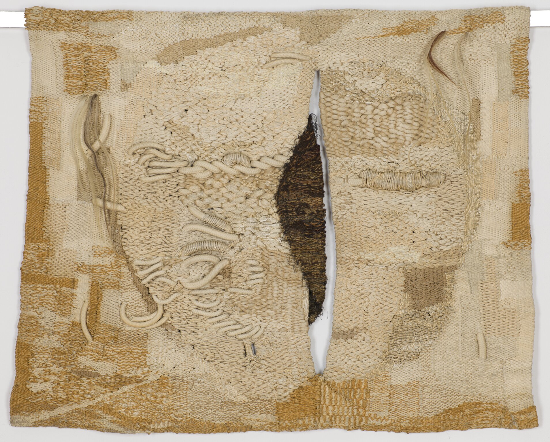 Praca autorstwa Magdaleny Abakanowicz pod tytułem „Biała” przedstawia prostokątny płat materiału, który pozszywany jest za pomocą różnej grubości nici. Mniej więcej w połowie długości tkaniny widoczna jest dziura, przez którą wystaje gruby brązowy materiał.