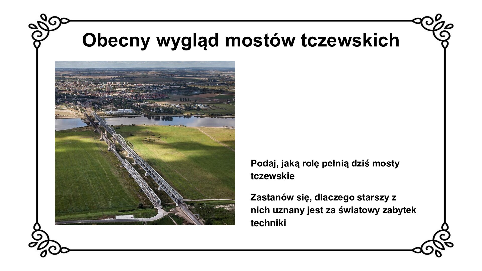 Slajd zawiera napis tytułowy: Obecny wygląd mostów tczewskich. Poniżej jest zdjęcie rzutu panoramicznego na mosty tczewskie. Mosty na zdjęciu biegną bardziej pionowo, w stronę poziomo płynącej rzeki i dalej miasta, początkowo nad zielonymi polami. Po prawej stronie most kolejowy, po lewej most drogowy zbudowane są równolegle względem siebie. Początkowo, mniej więcej do połowy budowli mosty wyglądają bliźniaczo - szare, proste, kratowe, stalowe konstrukcje. W dalszej części mosty różnią się od siebie. Most drogowy ma jasne filary przypominające wieże zbudowane na planie koła, z blankami i małymi oknami na trzech poziomach. Wieże podtrzymują tory zabudowane po bokach ciemną, zabytkową kratownicą. Most kolejowy ma szarą, prostą, łukową konstrukcję. W tle widać miasto. Zdjęciu, po prawej stronie,  towarzyszy napis ze zwrotem do ucznia: Podaj, jaką rolę pełnią dziś mosty tczewskie. Zastanów się, dlaczego starszy z nich uznany jest za światowy zabytek techniki.
