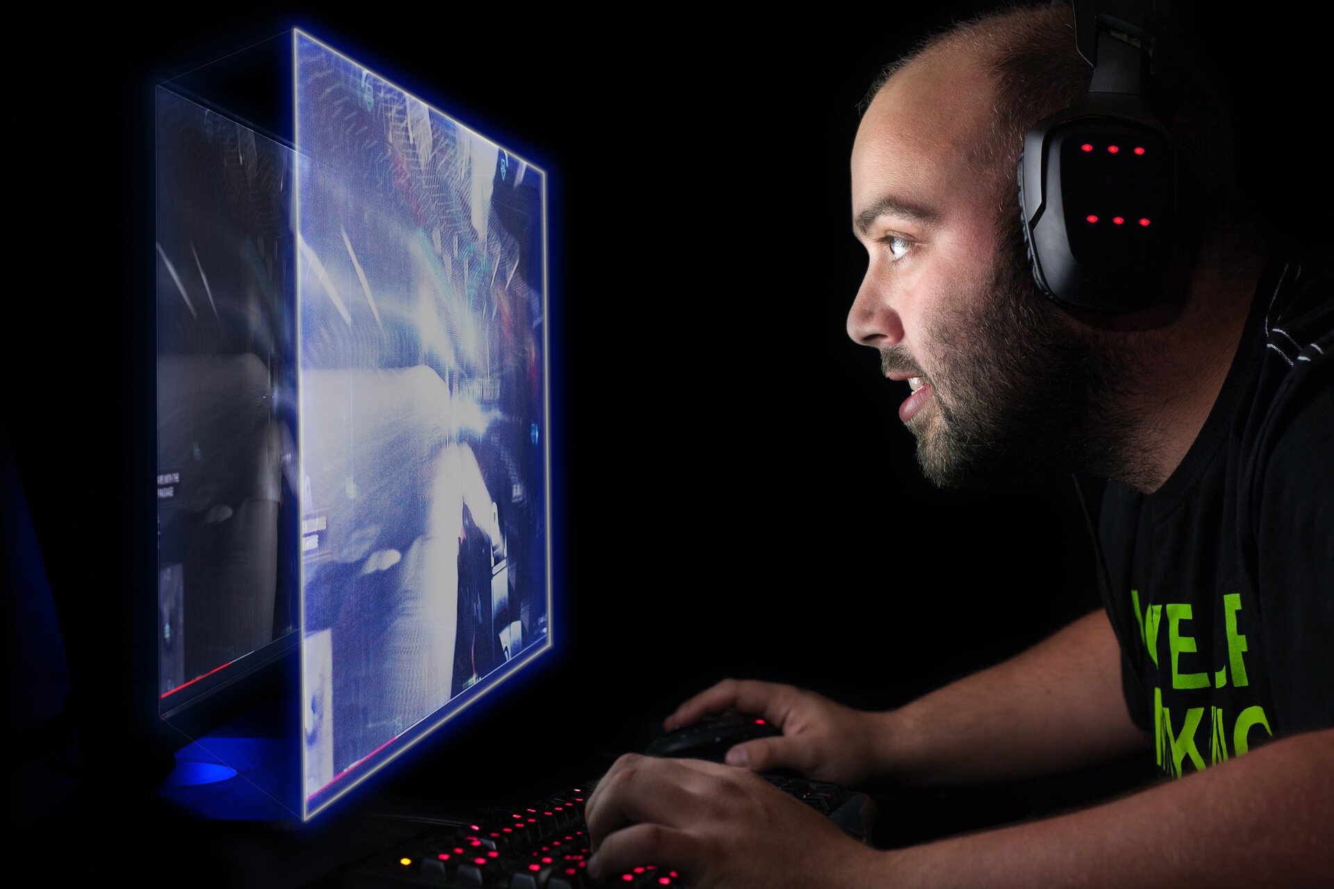 Ilustracja przedstawia wirtualną rzeczywistość. Zdjęcie ukazuje mężczyznę w wieku ok 35 lat, który siedzi ze słuchawkami na uszach i gra w grę komputerową. Mężczyzna korzysta z ekranu wyświetlającego obraz trójwymiarowy.