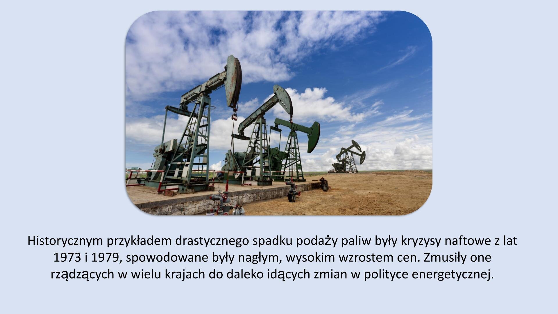 Jasnoniebieski slajd. U góry slajdu zdjęcie przedstawiające kiwony, które stoją na piaskowej powierzchni. U dołu slajdu tekst: „Historycznym przykładem drastycznego spadku podaży paliw są kryzysy naftowe w latach 1973 i 1979, które spowodowane były nagłym, wysokim wzrostem cen. Kryzysy te zmusiły rządzących w wielu krajach do daleko idących zmian w polityce energetycznej”.
