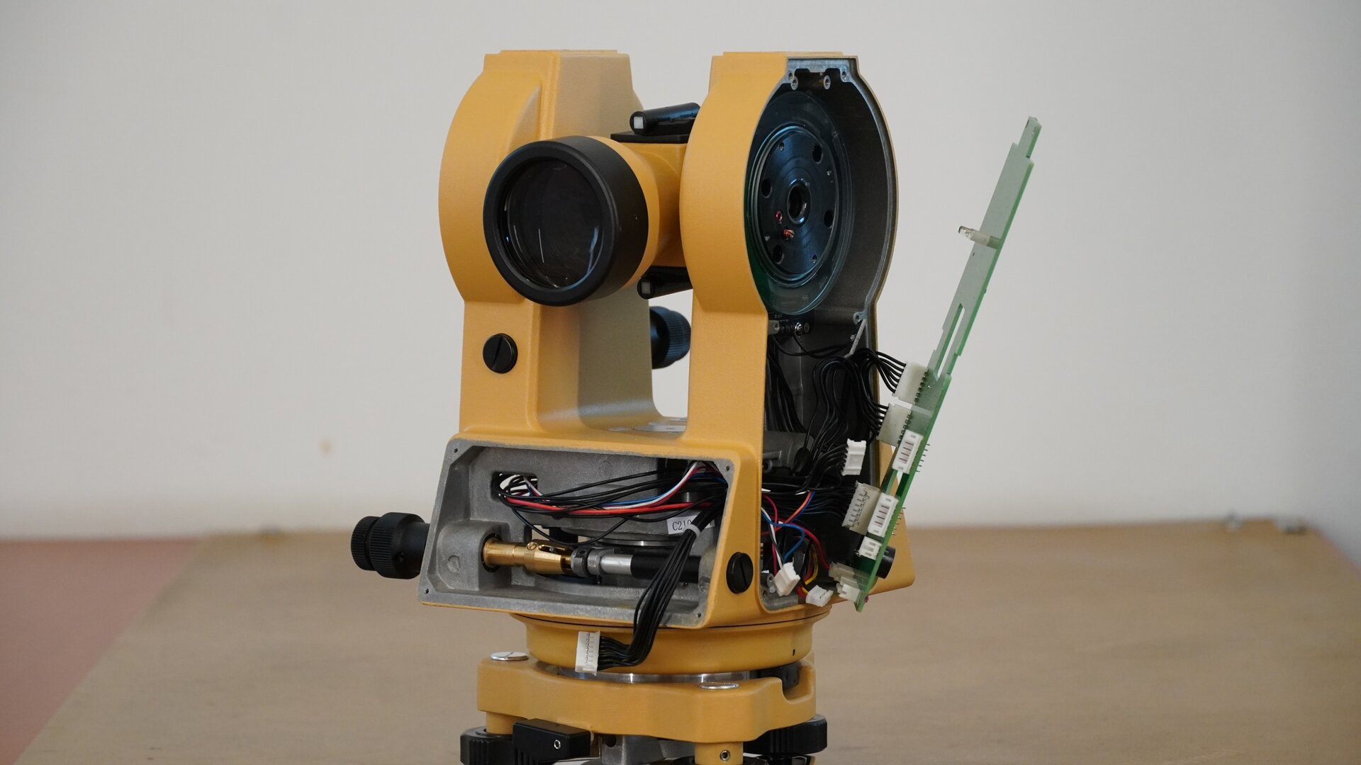 Na zdjęciu ukazano wewnętrzną budowę teodolitu. By to zrobić, zdemontowano boczną osłonę obudowy oraz panel z wyświetlaczem. Pod panelem widoczny jest mechanizm leniwki ruchu poziomego oraz przewody zespołów połączeń wyświetlacza.