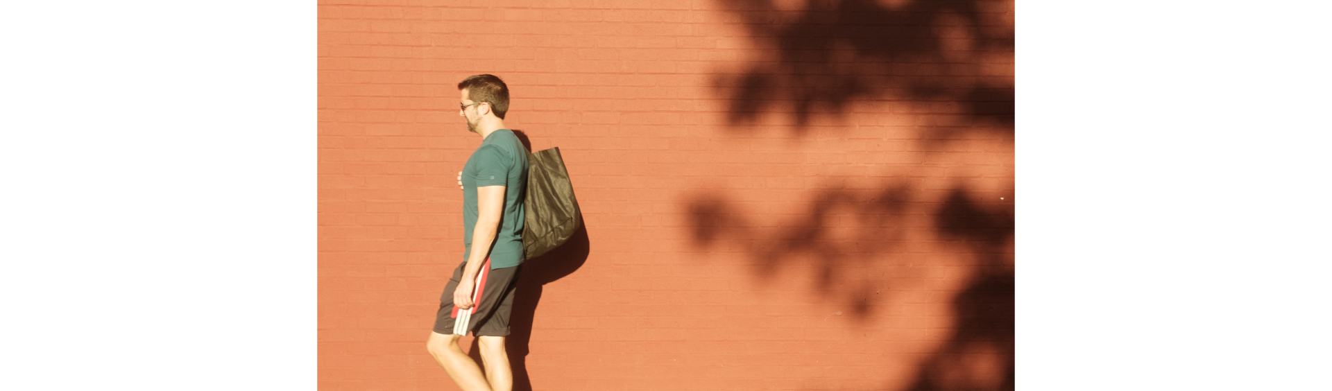 Ilustracja przedstawia mężczyznę wracającego z zakupów z torbą na tle ściany. 