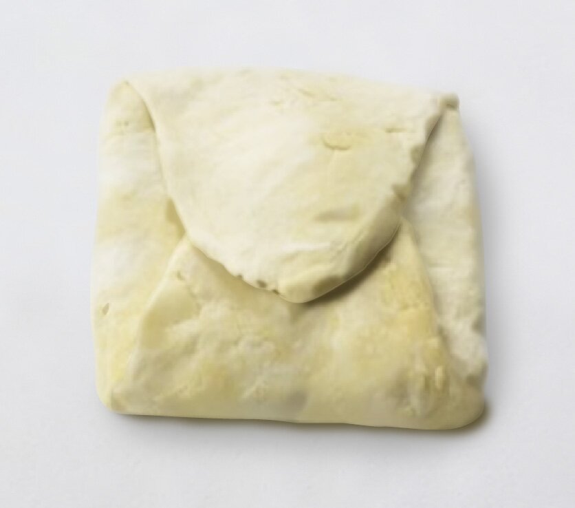 Zdjęcie przedstawia ciasto podstawowe, tzw. grunt. Widoczny jest fragment ciasta z końcami założonymi jeden na drugi, dzięki czemu wydłużony fragment stworzył kwadrat.