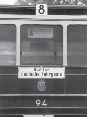 Zdjęcie przedstawia fragment wagonu tramwajowego z numerem osiem. Na wagonie zawieszona jest tabliczka z niemieckim napisem: Nur für deutsche Fahrgäste.