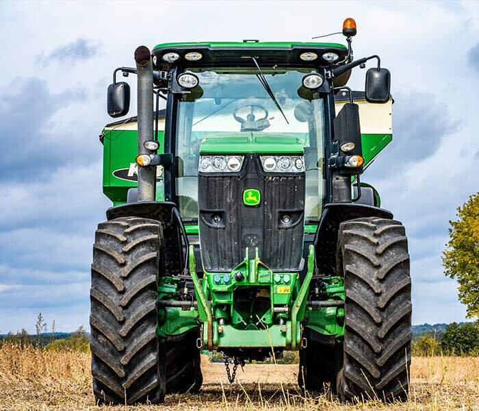 Zdjęcie czwarte przedstawia maszyny rolnicze. Pokazany jest traktor stojący na łące. Maszyna ta jest pomocna w hodowli koni, ponieważ za jego pomocą tworzone są snopki siana, wykorzystywane w żywieniu koni.