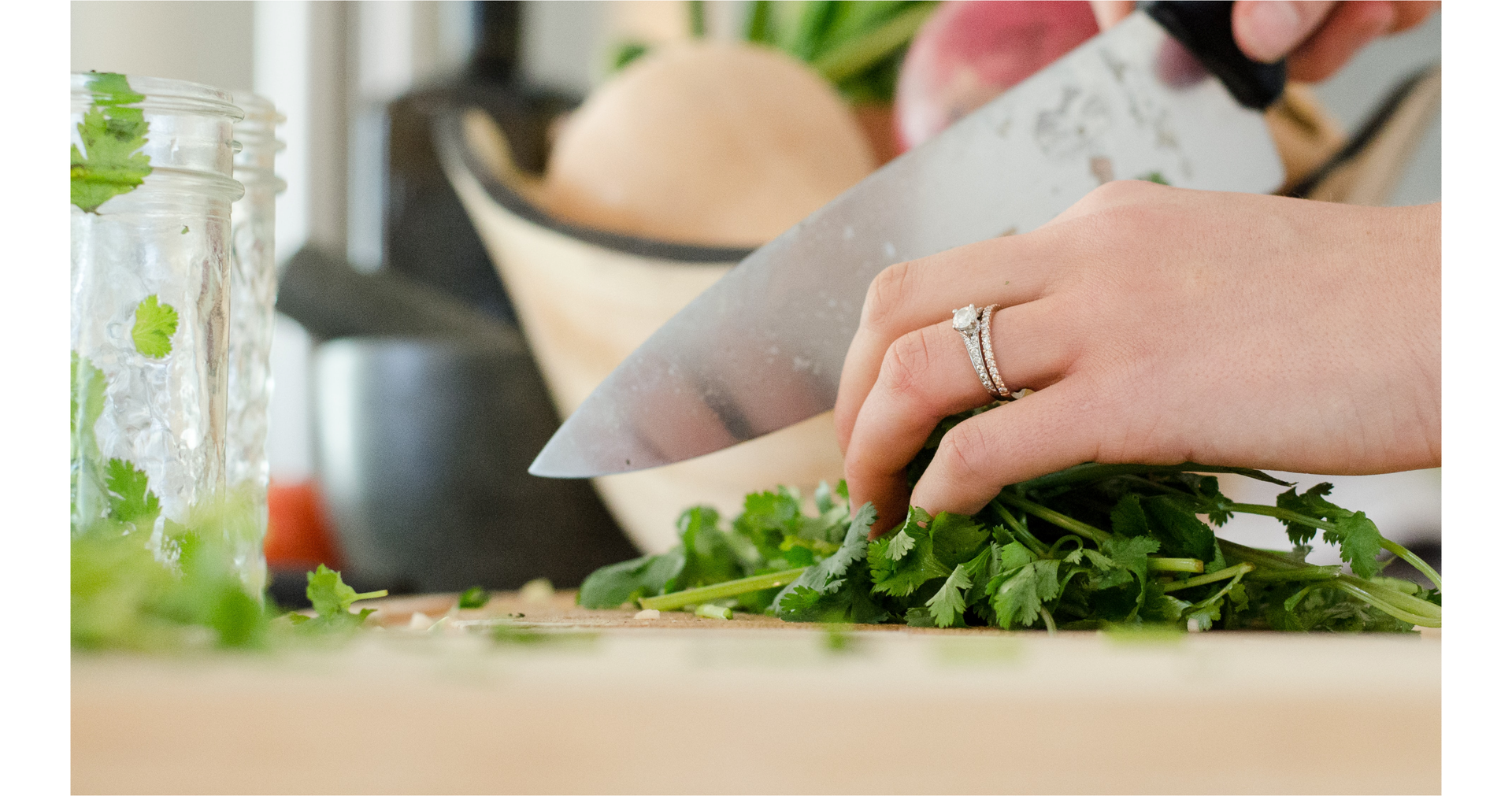 Zdjęcie przedstawia ręce osoby siekającej zieleninę na desce do krojenia.