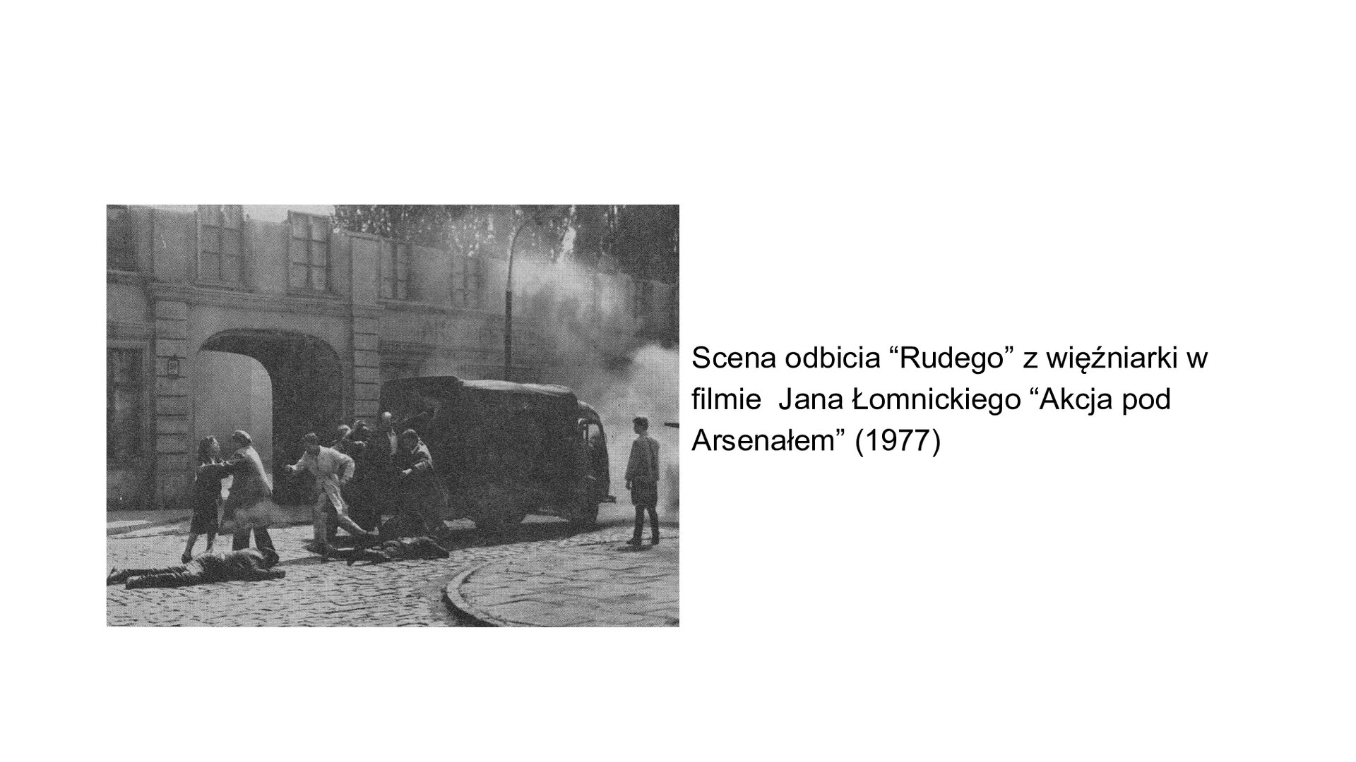 Slajd przedstawia kadr filmowy ze sceną odbijania więźniów z ciężarówki -więźniarki. Grupa osób stłoczona w pobliżu tylnych drzwi pojazdu. W tle klasycystyczne zabudowania kamienic miejskich. Scena rozgrywa się na ulicy. Tekst po prawej stronie slajdu: Scena odbicia "Rudego" z więźniarki w filmie Jana Łomnickiego "Akcja pod Arsenałem" (1977).