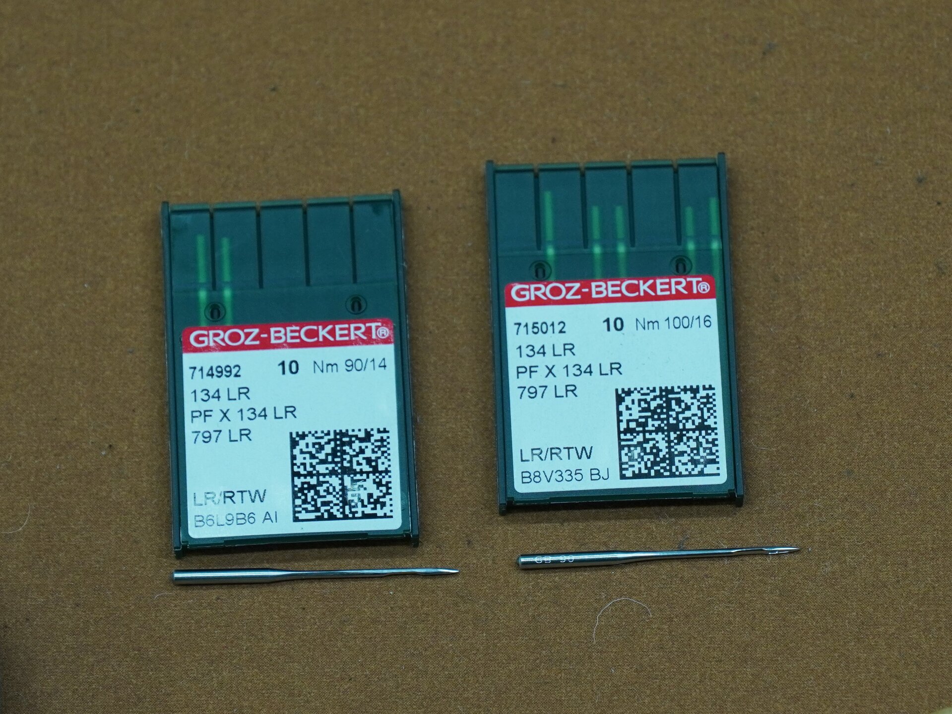 Zdjęcie przedstawia dwa małe, płaskie czarne półprzezroczyste pudełka z białymi etykietami. Na dole każdego z tych pudełek leży w poprzek igła. Nagranie tożsame z treścią.