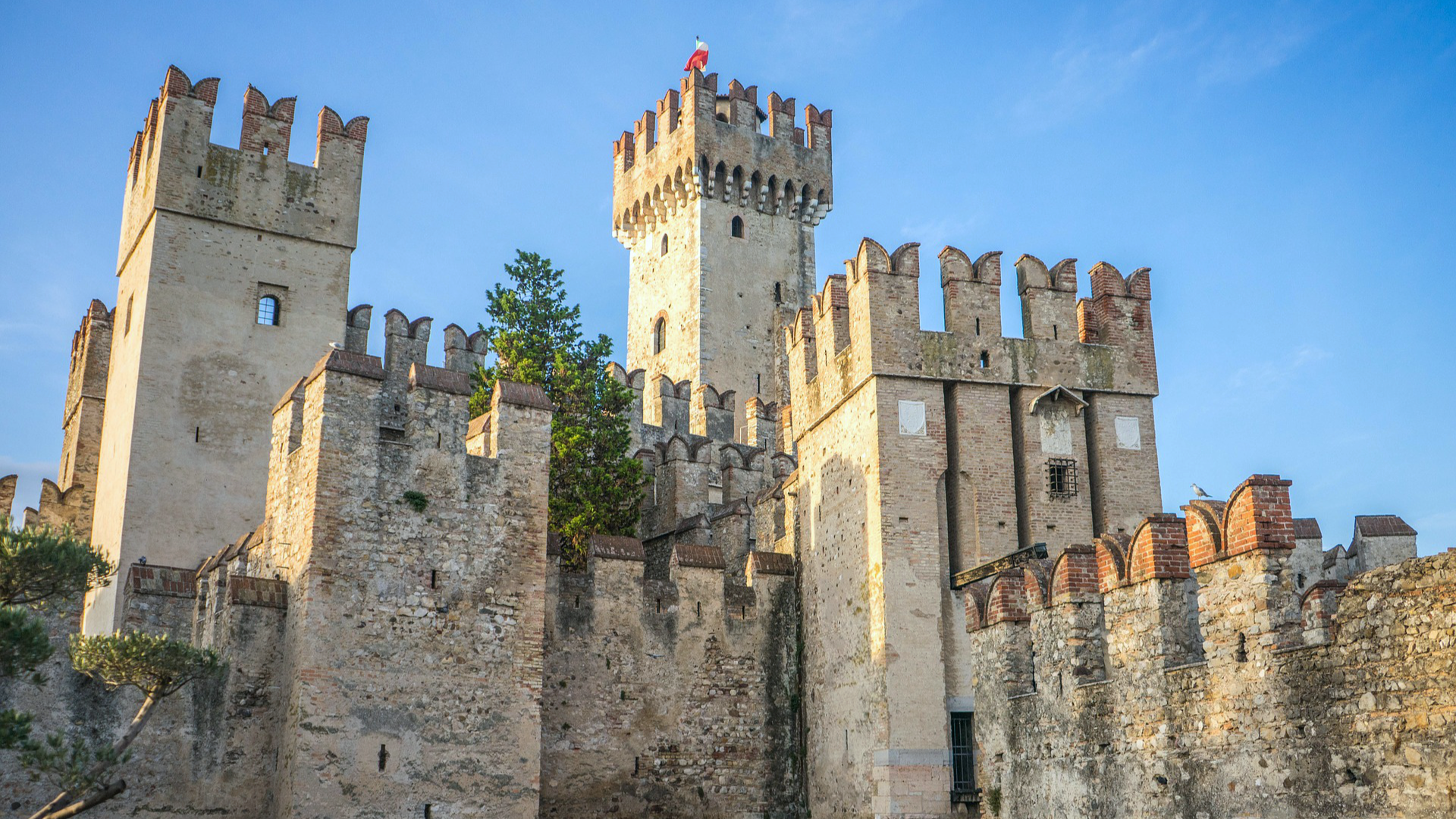 Zdjęcie przedstawia zamek w Sirmione. Widoczne są wysokie wieże obronne.