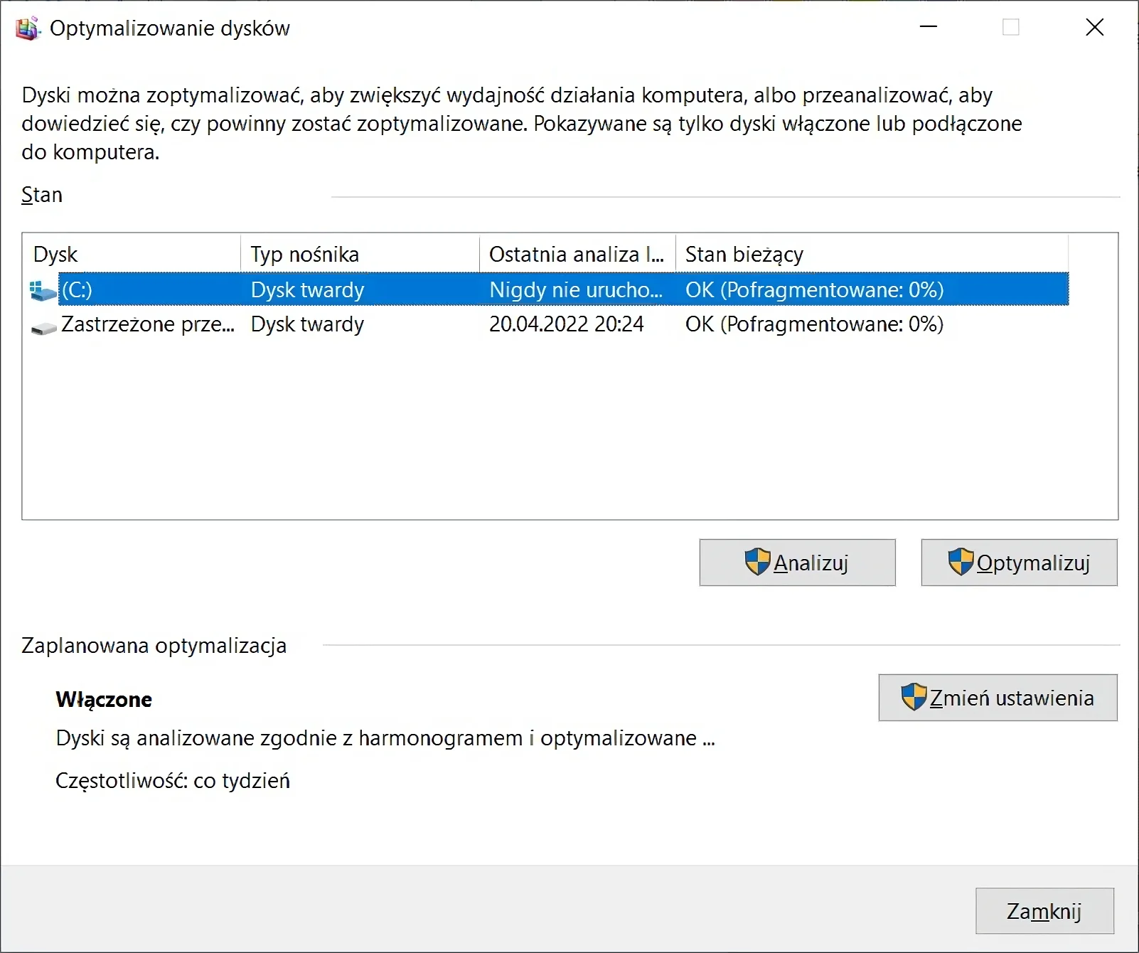 Ilustracja przedstawia okno Optymalizowanie dysków systemu Windows. Na samej górze znajduje się informacja: Dyski można zoptymalizować, aby zwiększyć wydajność działania komputera, albo przeanalizować, aby dowiedzieć się, czy powinny zostać zoptymalizowanie. Pokazywane są tylko dyski włączone lub podłączone do komputera. Poniżej na liście znajdują się dwa dyski. Pod listą znajdują się przyciski Analizuj oraz Optymalizuj. Na dole znajduje się sekcja Zaplanowana optymalizacja, jest ona włączona. Po prawej stronie znajduje się przycisk Zmień ustawienia. Na samym dole znajduje się przycisk Zamknij.