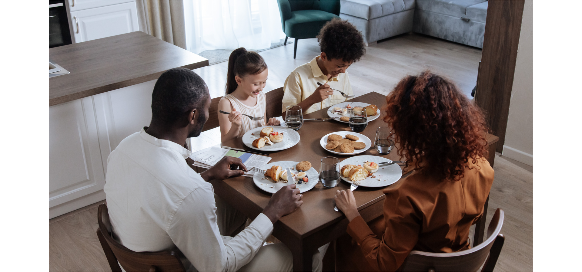 Zdjęcie przedstawia czteroosobową rodzinę: rodziców i dwoje dzieci siedzących przy stole w jadalni w czasie śniadania.
