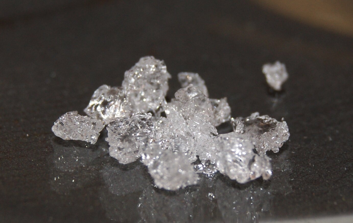 Zdjęcie przedstawia bezbarwne, mieniące się grube kryształy.