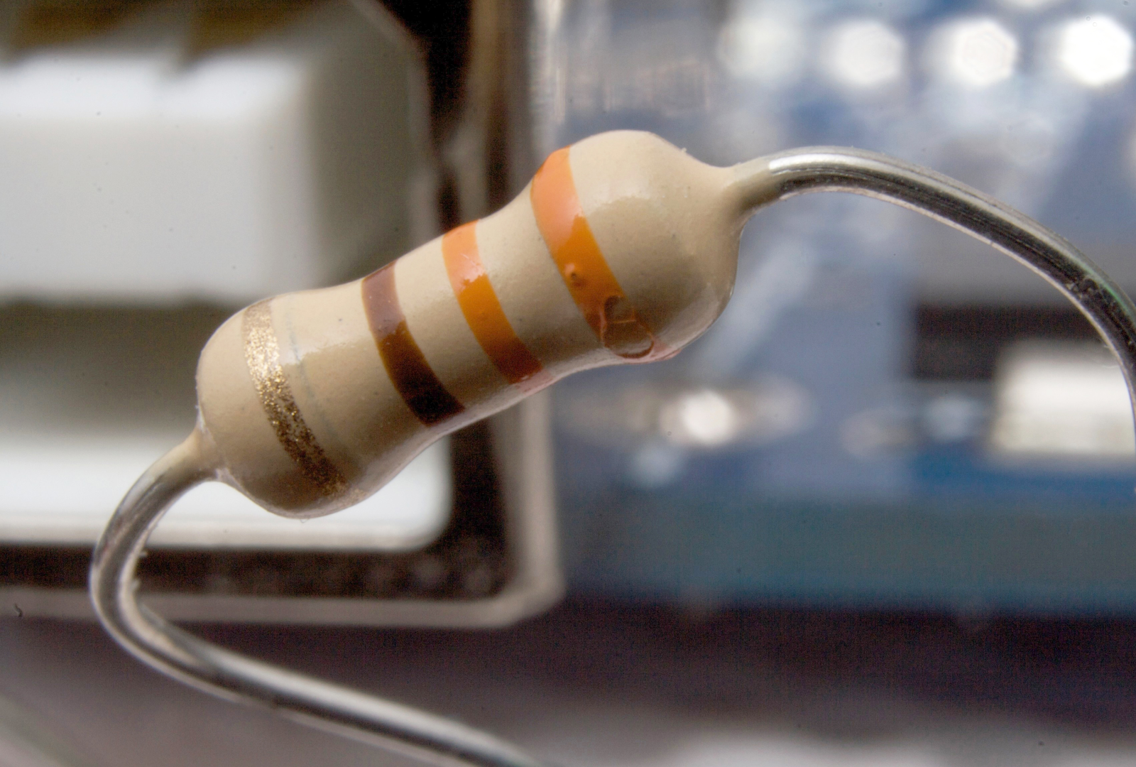 Zdjęcie przedstawia opornik o mocy 0,5 wata. Jest  to element, który służy do ograniczania przepływu prądu w obwodzie elektrycznym. Opornik jest wykonany z ceramiki a jego kształt jest obły. Z jednej i drugiej strony korpusu widoczne są druty, które umożliwiają jego połączenie z innymi elementami w obwodzie elektrycznym. 