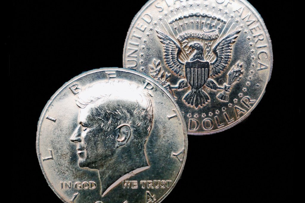 Ilustracja przedstawia awers i rewers srebrnej monety - dolara.