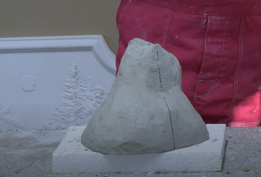 Zdjęcie przedstawia formę gipsową średniej wielkości o nieregularnym kształcie. Forma znajduje się na kamiennej płaszczyźnie.