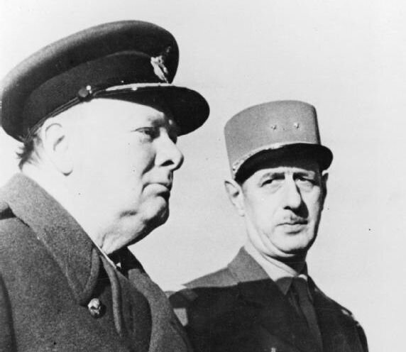 Zdjęcie przedstawia dwóch mężczyzn w mundurach wojskowych. Po lewej stronie stoi odwrócony prawym profilem do widza Winston Churchill. Stojący po prawej stronie Charles de Gaulle przygląda się mu.
