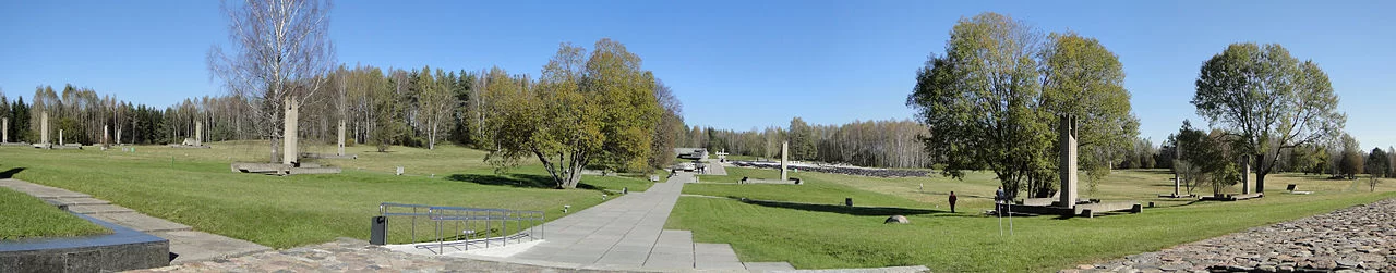 Na zdjęciu widoczne są zielone trawniki i drzewa oraz chodniki. Gdzieniegdzie na trawniku widoczne są pojedyncze słupy kamienne. W tym miejscu kiedyś była wioska Chatyń.