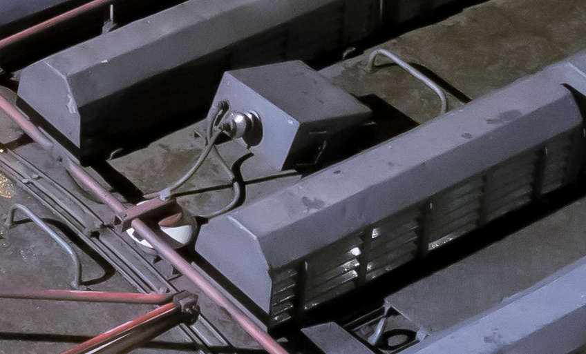 Ilustracja przedstawia odgromnik. Odgromnik znajduje się na dachu lokomotywy, jest w kształcie skrzyni i jest zamontowany pod kątem ostrym. Odgromnik połączony jest z szyną.