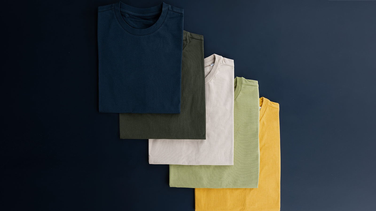 Zdjęcie przedstawia pięć ułożonych w kostkę koszulek. Każda z nich jest innego koloru.