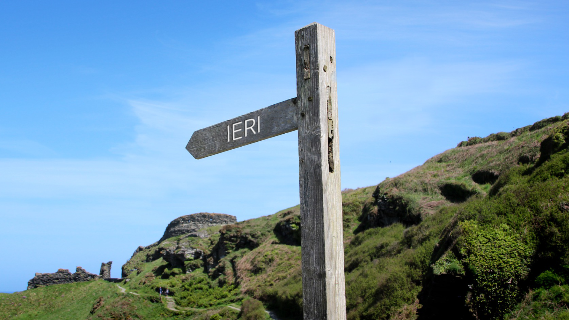 Zdjęcie przedstawia krajobraz górski. Na pierwszym planie znajduje się drogowskaz, na którym oznaczony jest kierunek z napisem: "ieri".