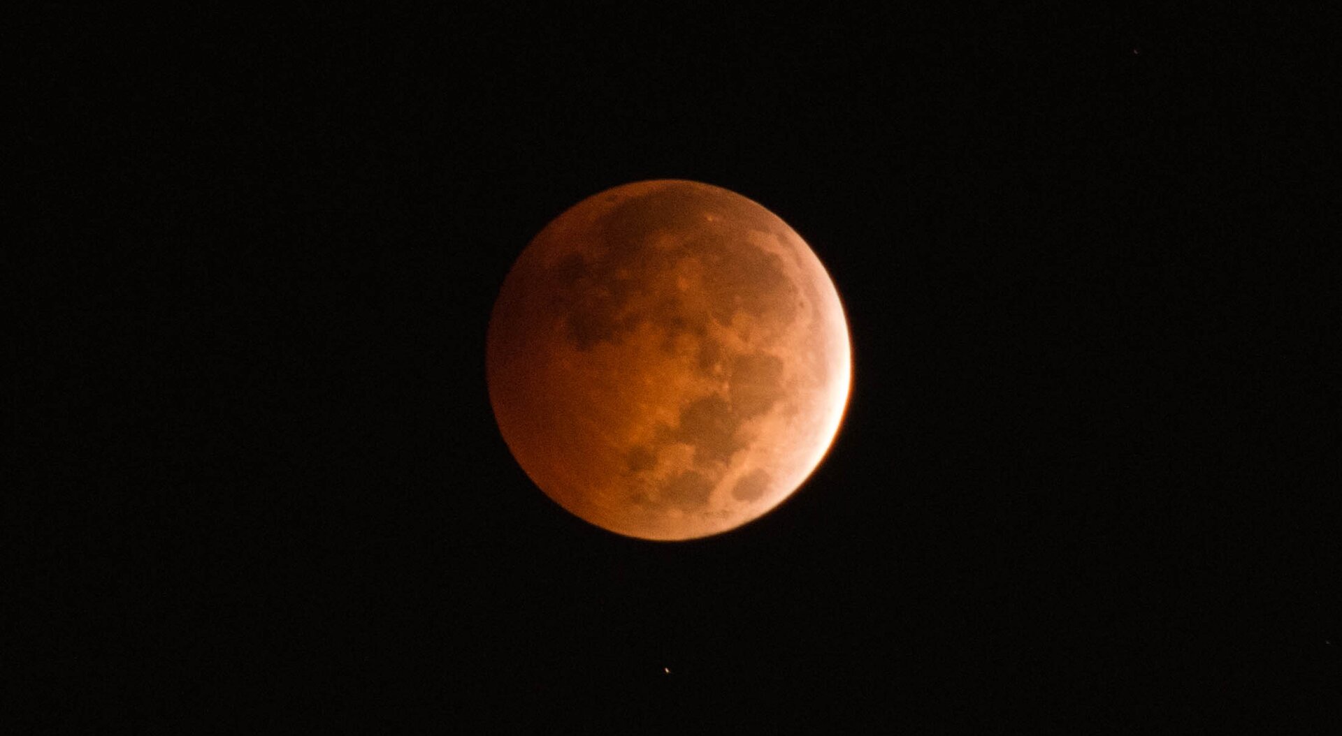 Księżyc w momencie bliskim całkowitego zaćmienia. Jest widoczny, ale przybiera barwę brunatno‑czerwoną.