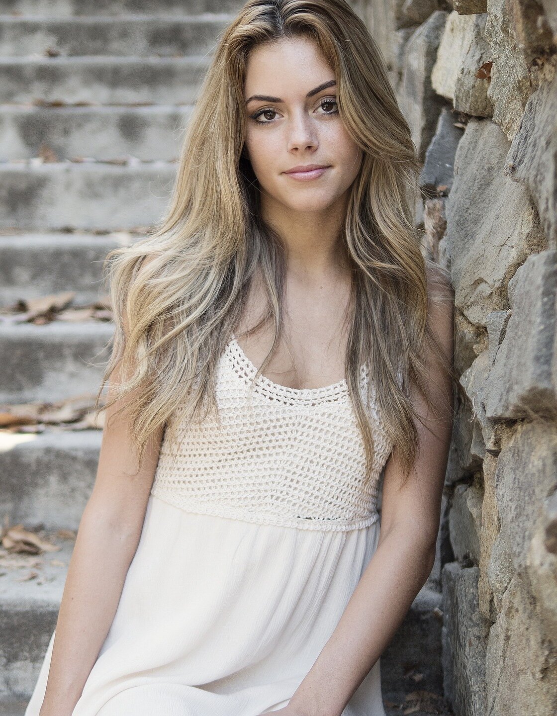 Na zdjęciu znajduje się młoda, długowłosa kobieta w jasnej sukience.